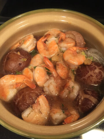 cooked shrimps, shiitake mushrooms and vermicelli noodles immersed in water in clay pot