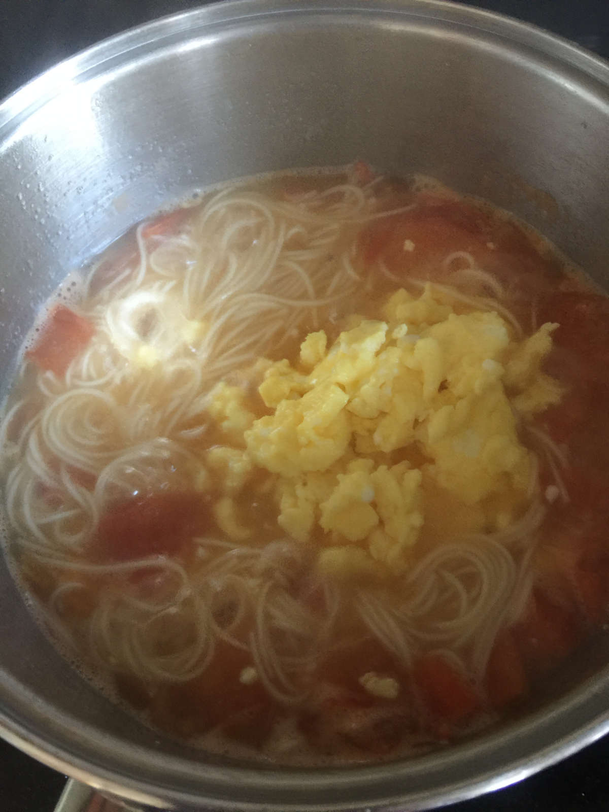 add cooked scrumble eggs to tomato noodle soup in pot