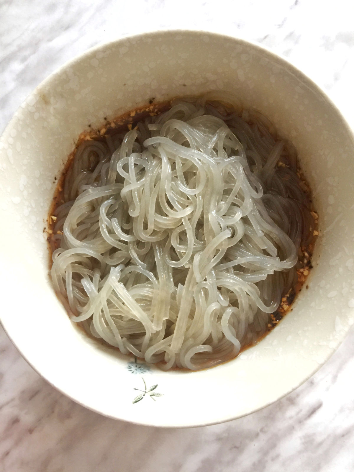 Overhead view of cooked sweet potato glass noodles placed in a beige bowl.