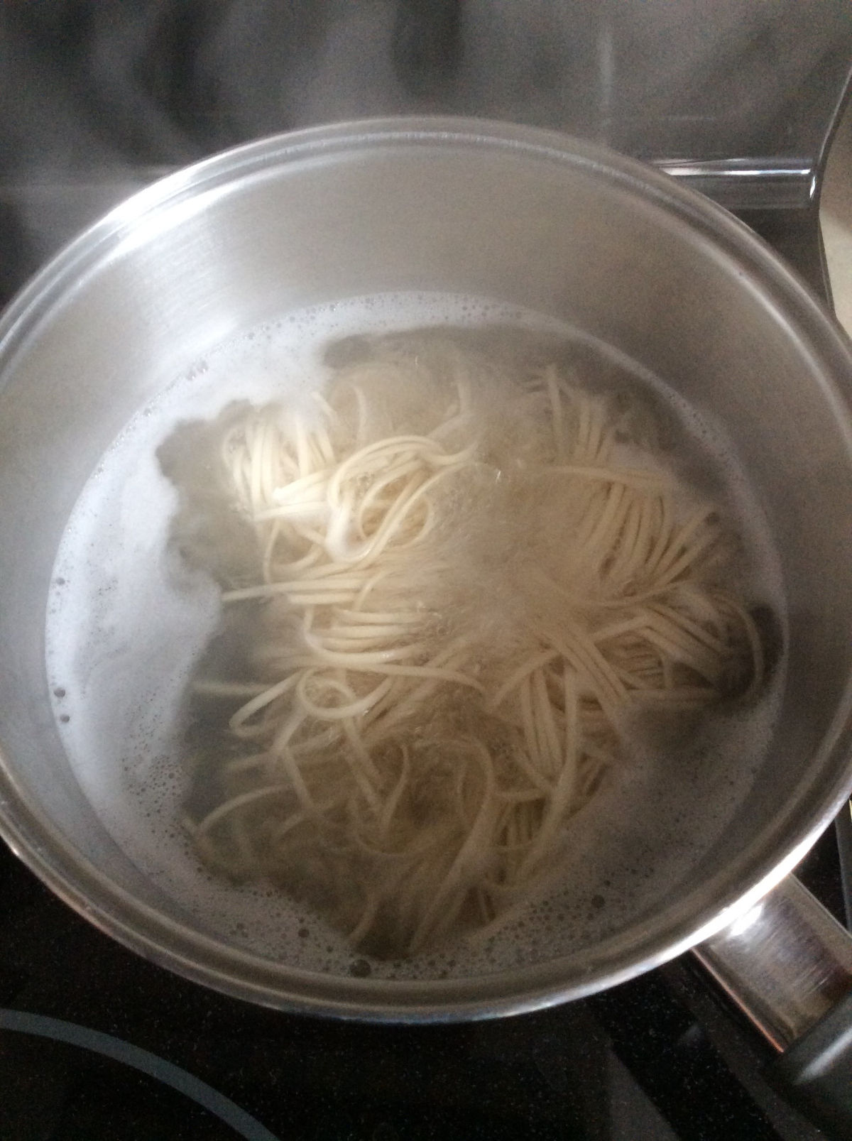 Close up view of noodles cooking in boiling water in a pot.