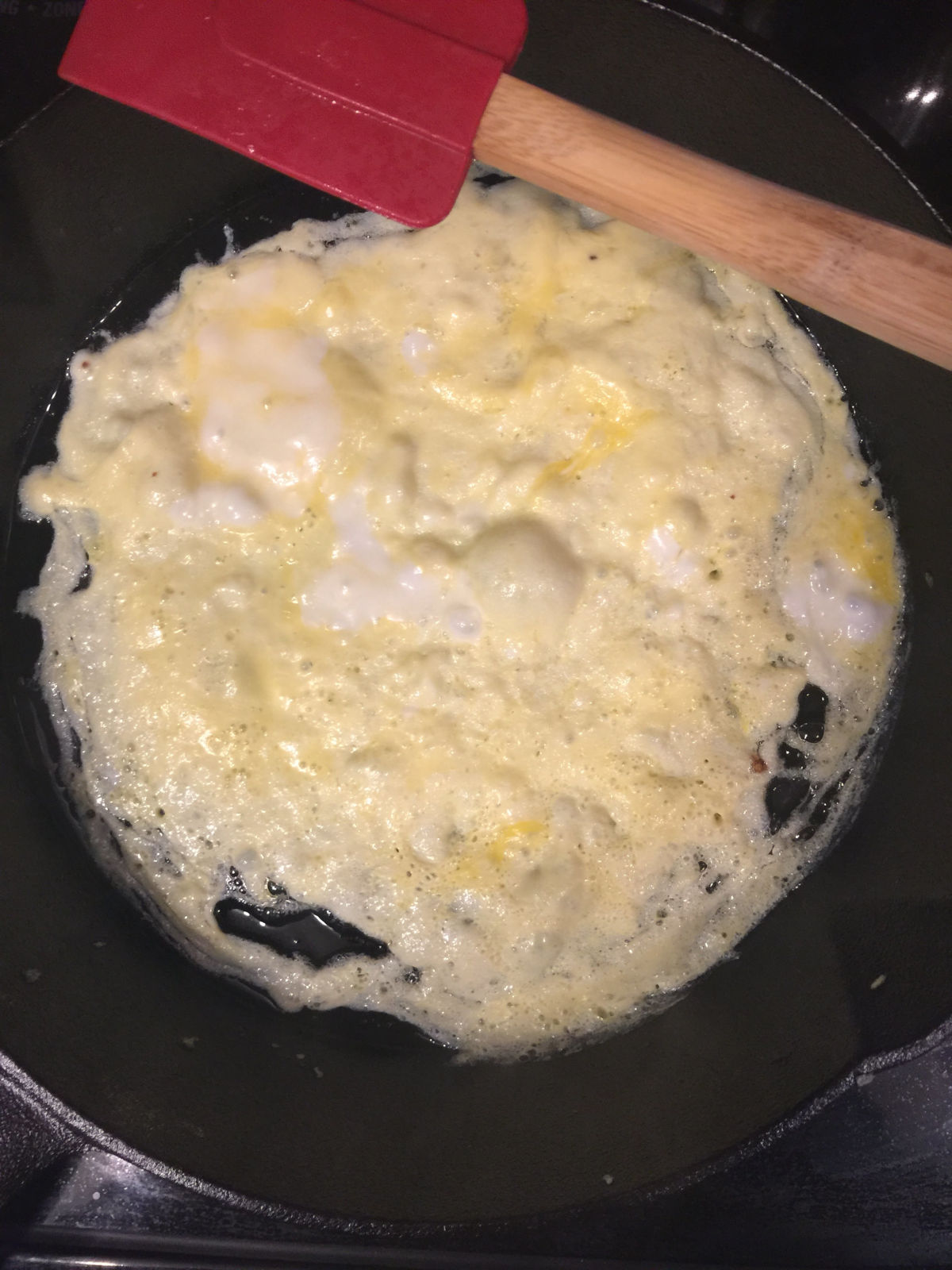 Overhead view of egg cooking in iron skillet.