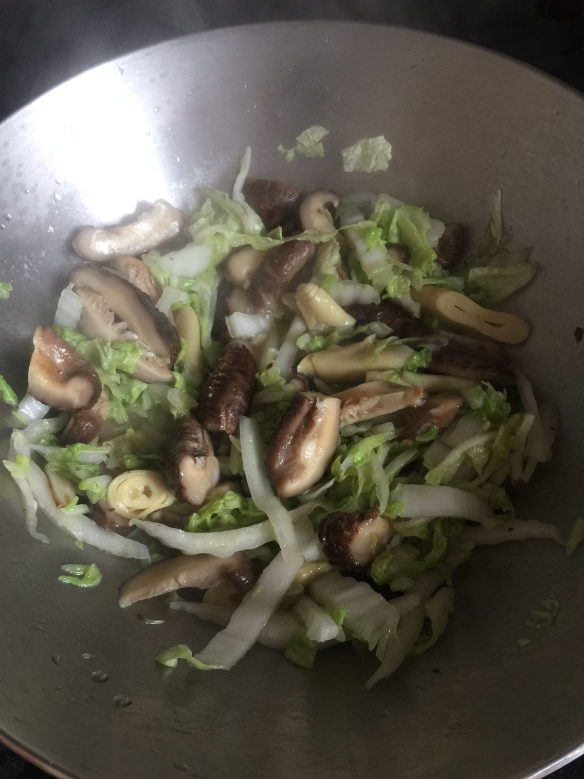 A close up view of vegetables cooking in a stainless steel wok.