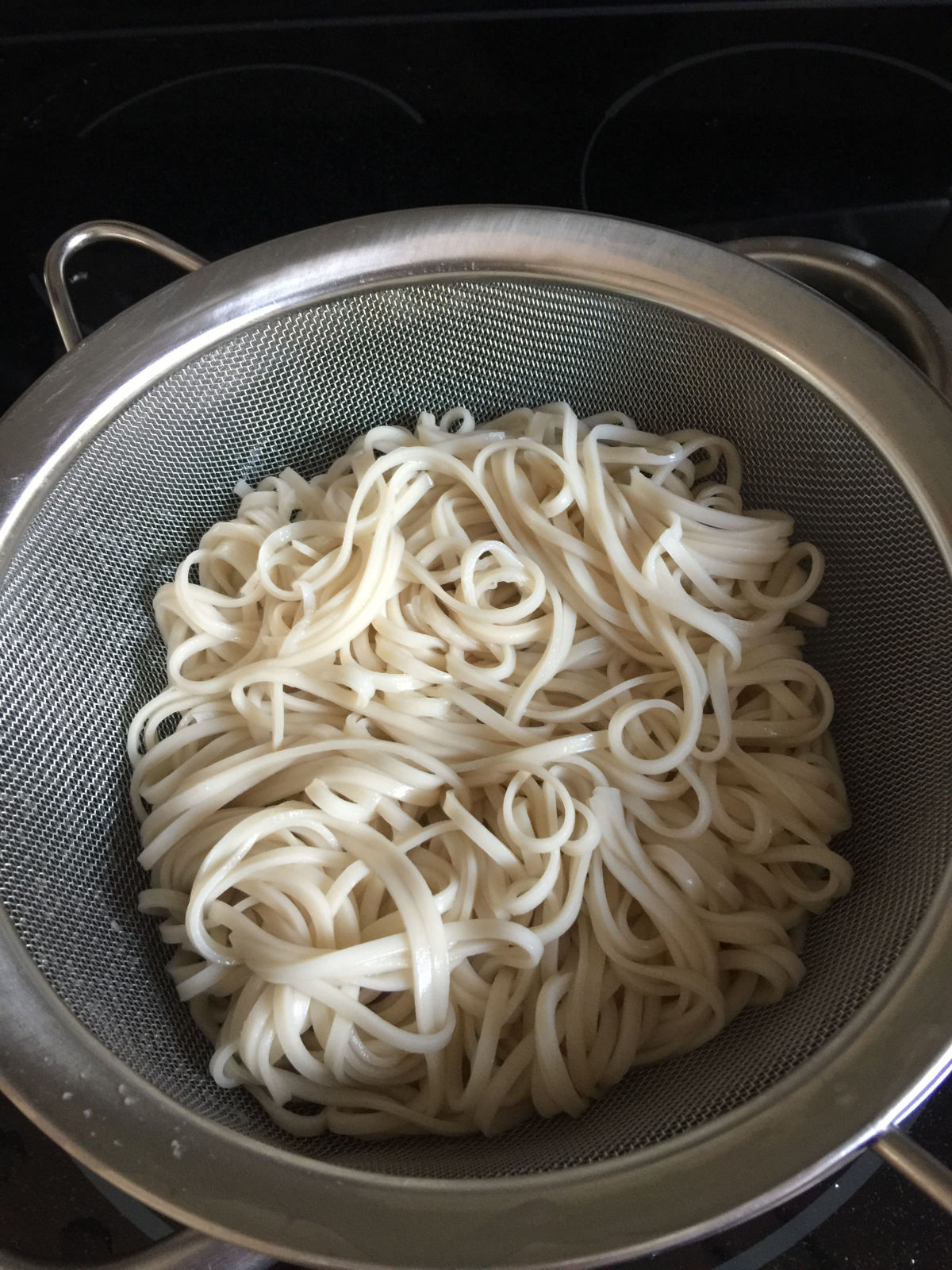 Overhead view of noodles draining in a strainer.