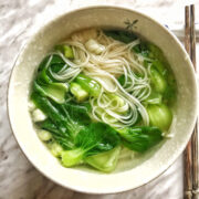 Overhead view of a bowl of noodle soup next to a pair of chopsticks resting on the chopstick stand.