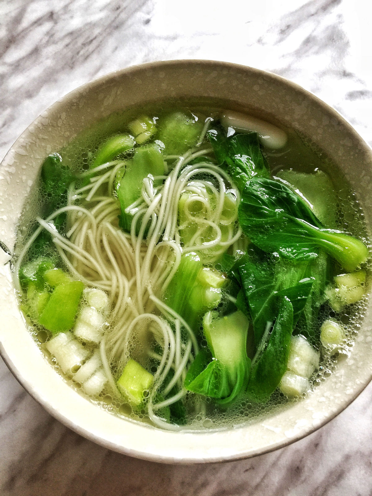 Close up view of a bowl of finished noodle soup.