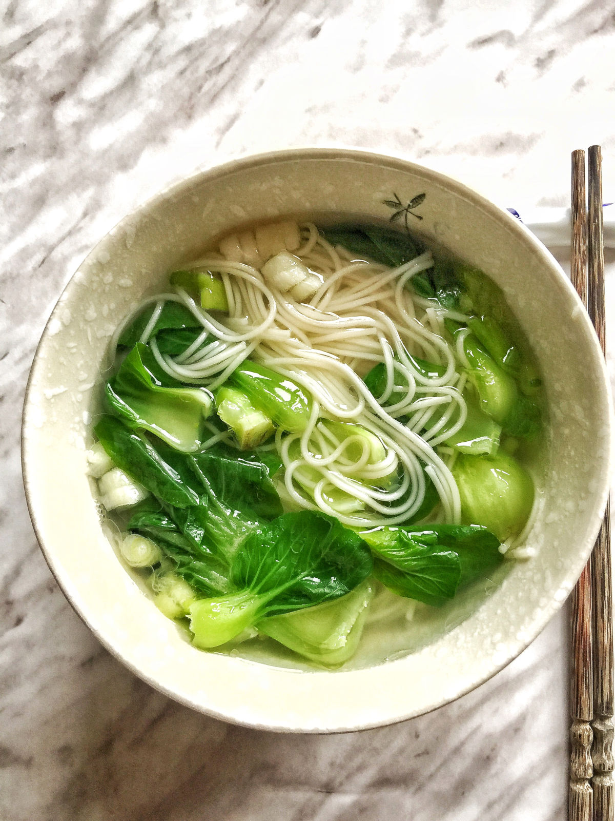 Overhead view of a bowl of cooked noodle soup with chopsticks on the side.