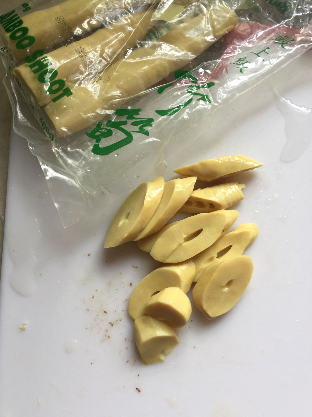 Small pieces of bamboo shoots on cutting board next to a package of bamboo shoot.