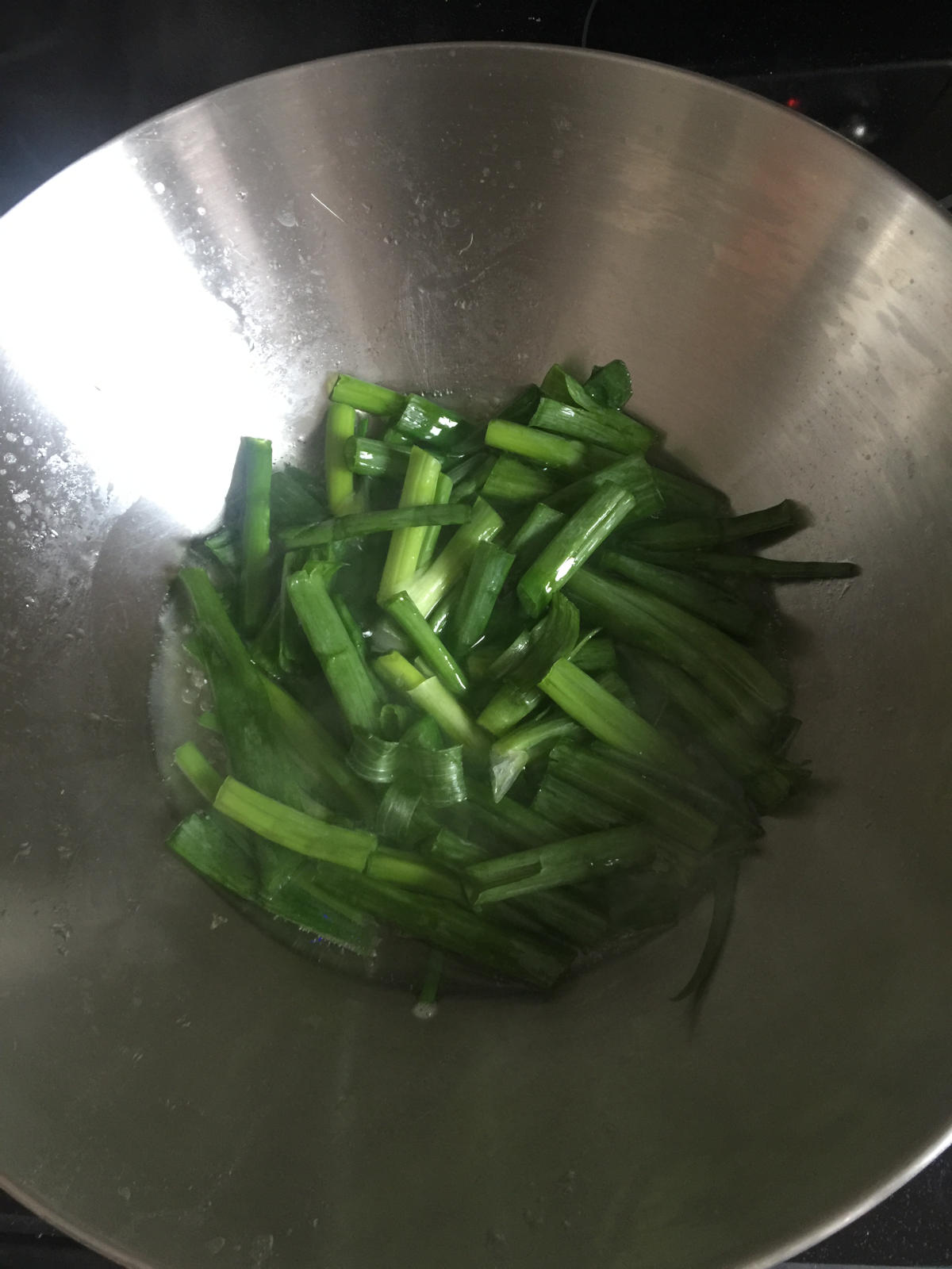 Scallion strips are cooking in wok.
