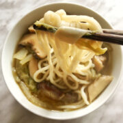 A close-up view of a bowl of cooked vegetable noodle soup.