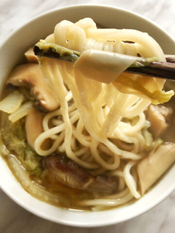 A close-up view of a bowl of cooked vegetable noodle soup.